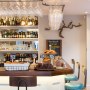 The Oxford Wine Cafe | Bar detail showing commissioned high level wine glass storage.  A piece of vine from France is displayed on the wall at the back | Interior Designers